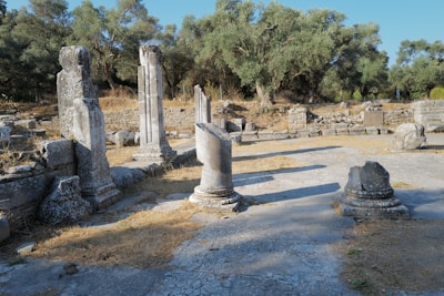 Ruins of ancient columns standing tall among scattered stones and greenery.