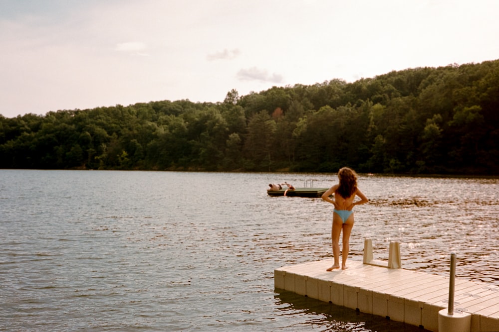 woman in pink bikini sitting on brown wooden dock during daytime