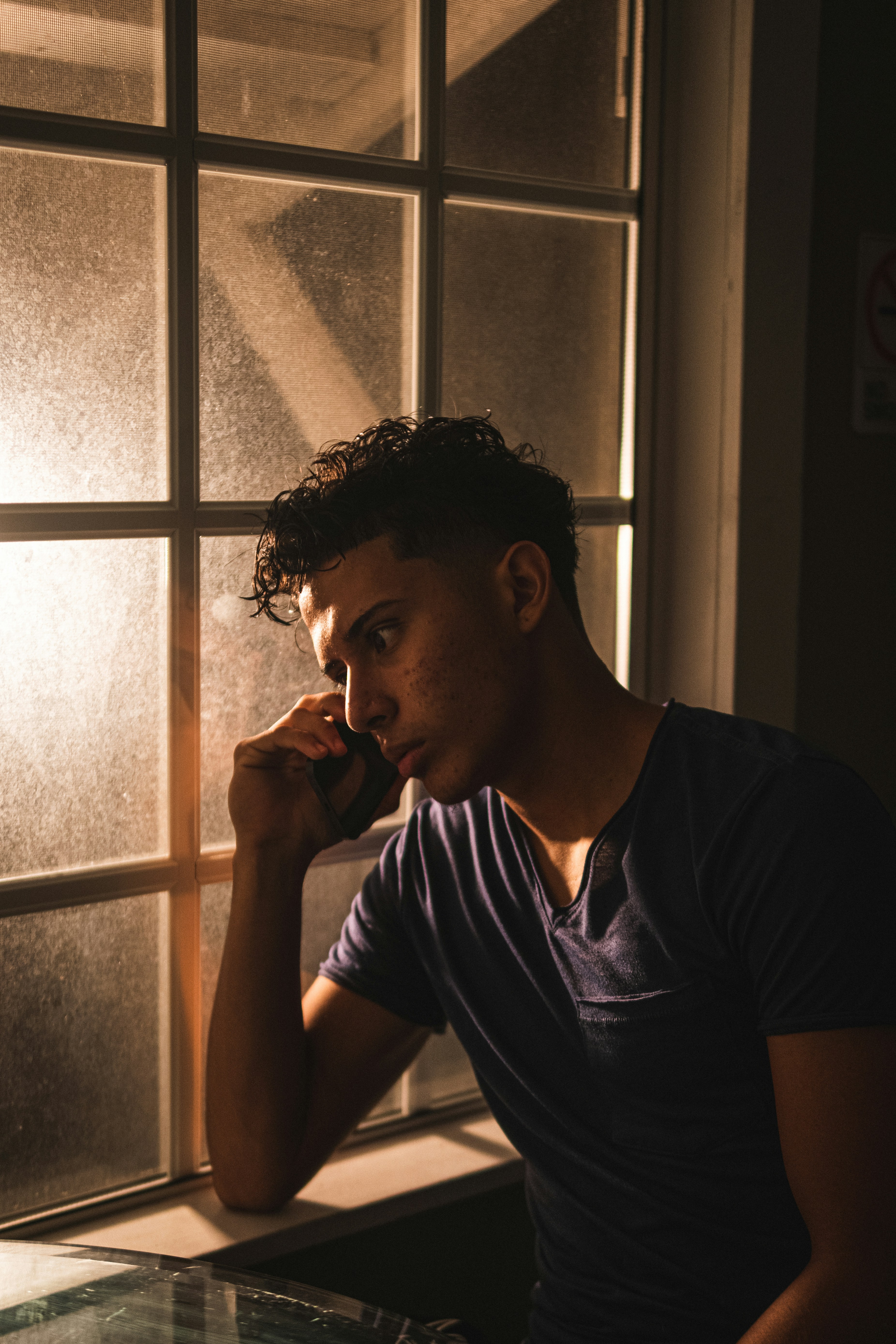 Mann im schwarzen Rundhals-T-Shirt in der Nähe der Glasscheibe