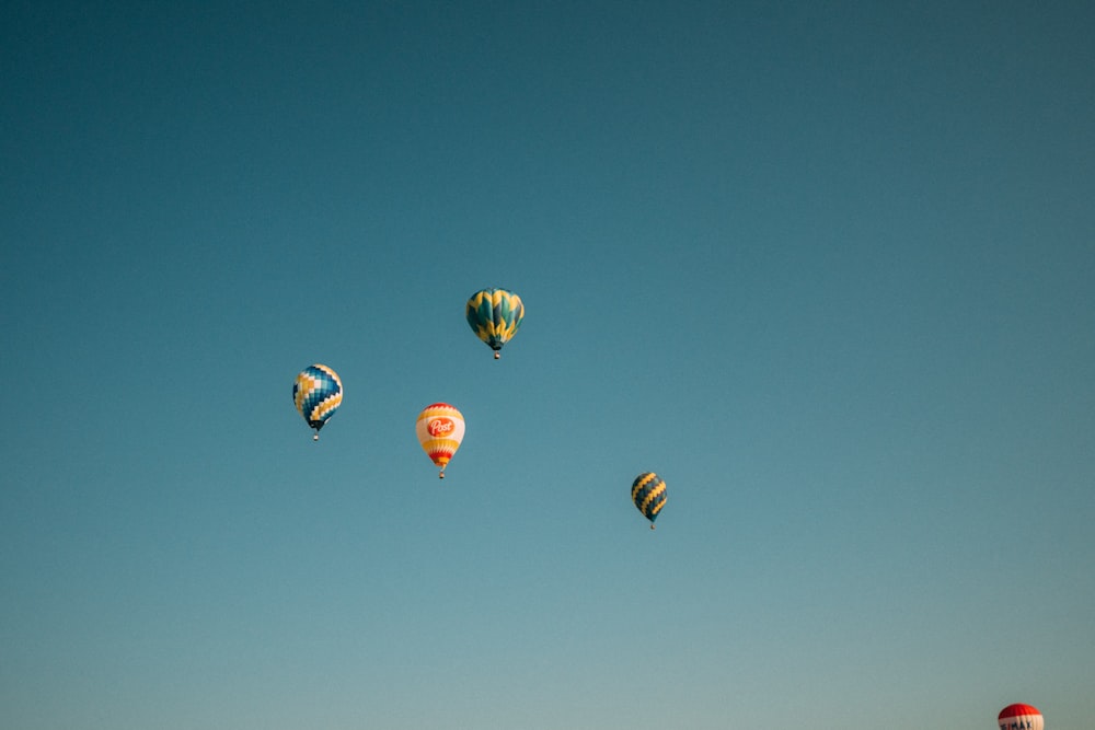 yellow green and red hot air balloon in mid air under blue sky during daytime