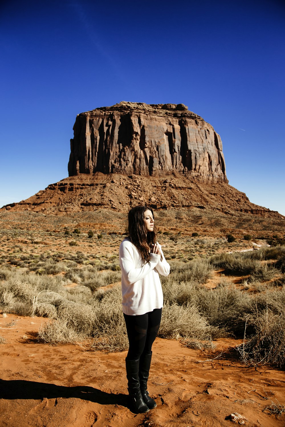 woman in white long sleeve shirt and black pants standing on brown grass field during daytime