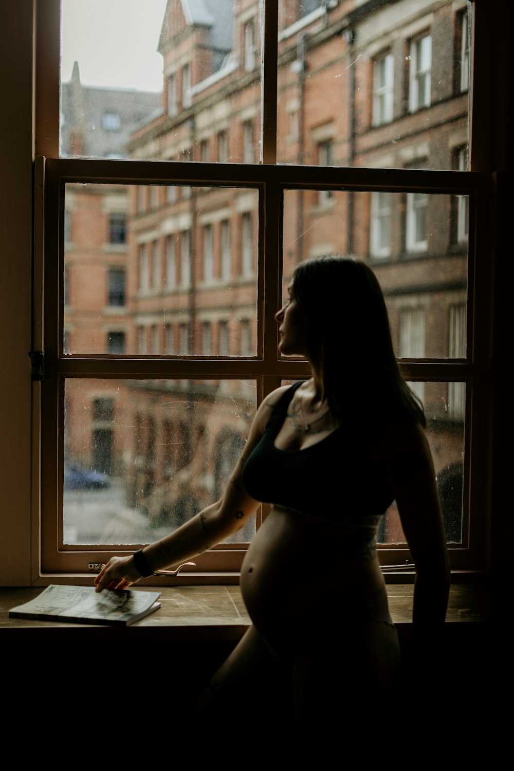 woman in black tank top sitting by the window