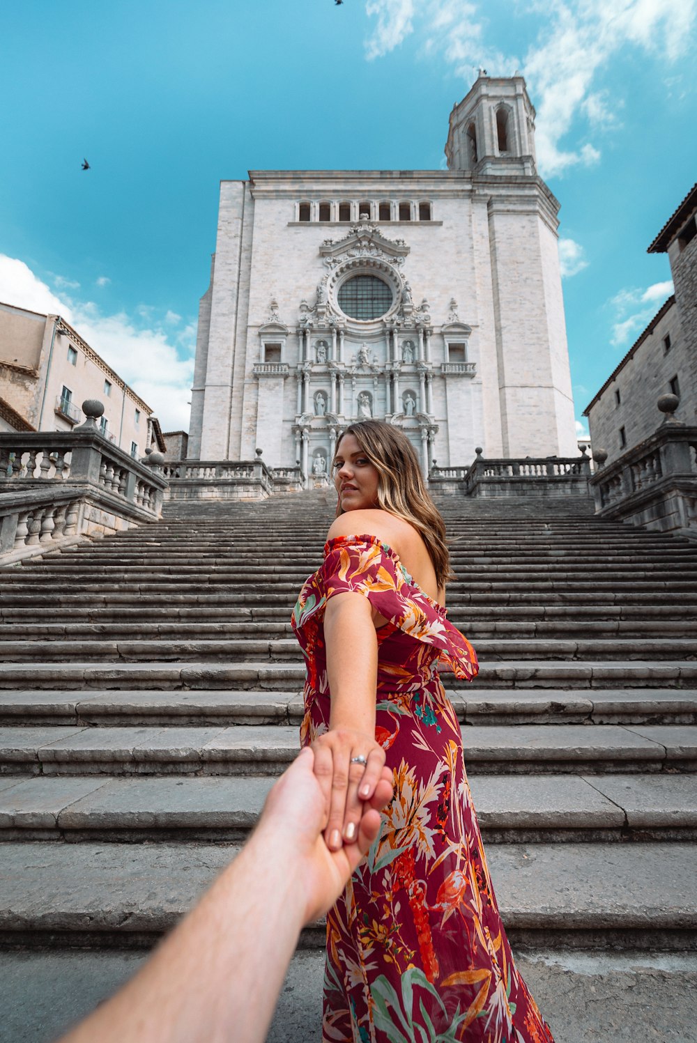 woman in red and white floral dress sitting on stairs