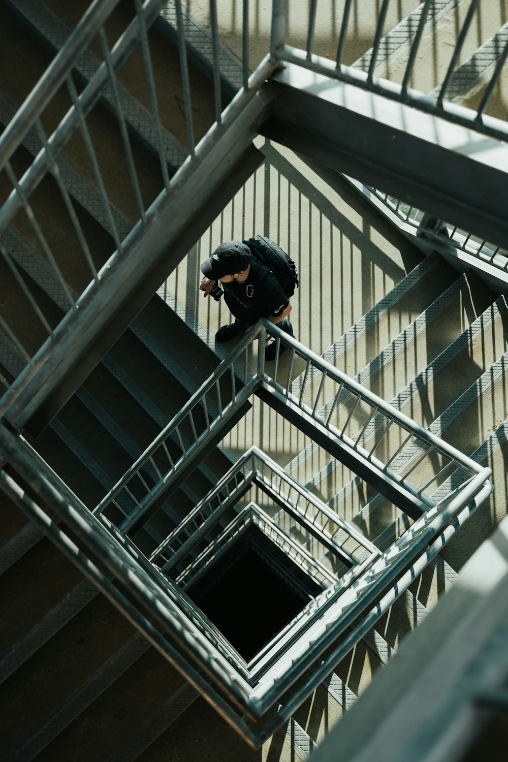 灰色のコンクリートの階段に立つ黒いジャケットと黒い帽子の男