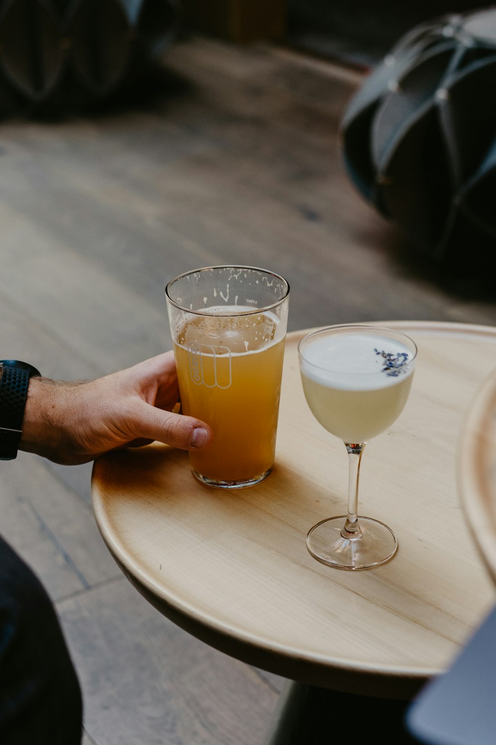 person holding clear drinking glass with yellow liquid