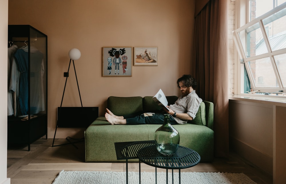 man and woman sitting on green sofa