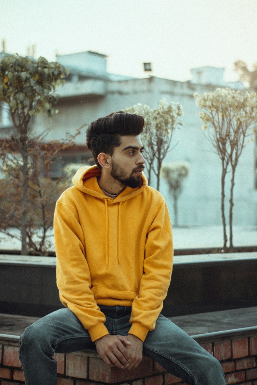 man in yellow hoodie sitting on bench during daytime