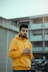 man in yellow hoodie standing near white building during daytime