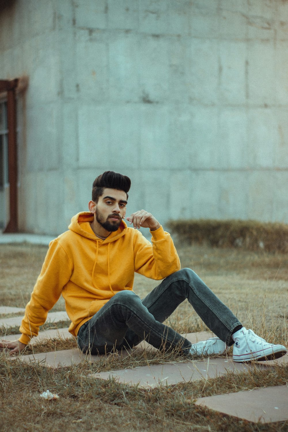 garçon en sweat à capuche jaune et jean bleu assis sur le sol pendant la journée