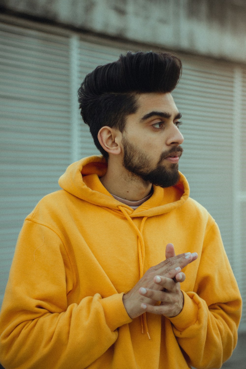 man in yellow hoodie holding his chin