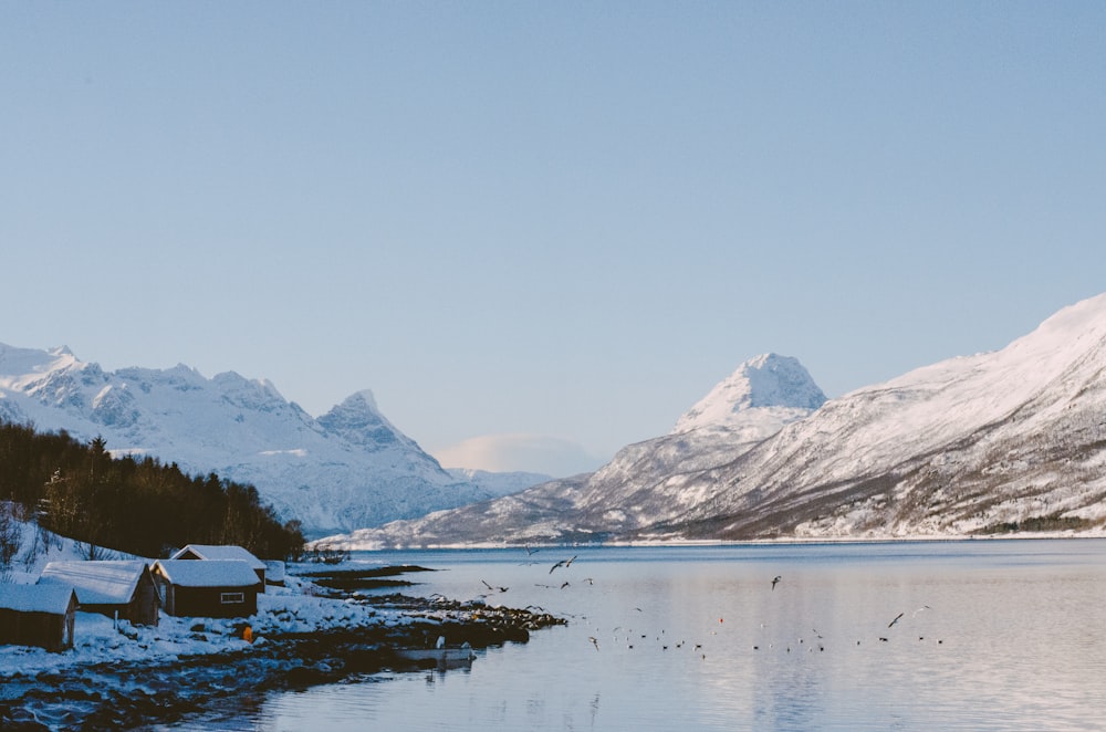 a body of water surrounded by snow covered mountains