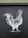 A monochrome illustration of a rooster is depicted on a dark surface. The drawing features intricate line work, highlighting the rooster's feathers and form against a flat backdrop.