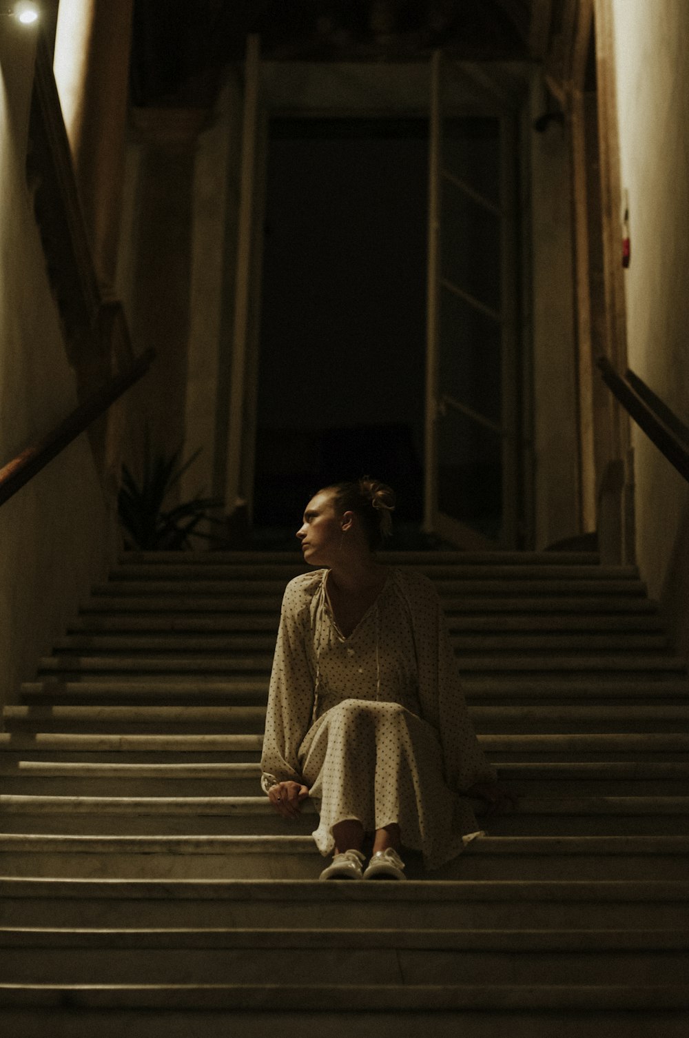 Frau in weiß-schwarzem Langarmkleid sitzt auf der Treppe