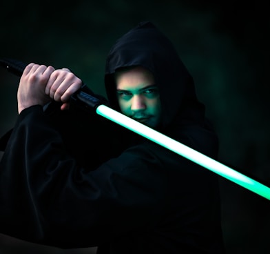 person in black hoodie holding blue stick