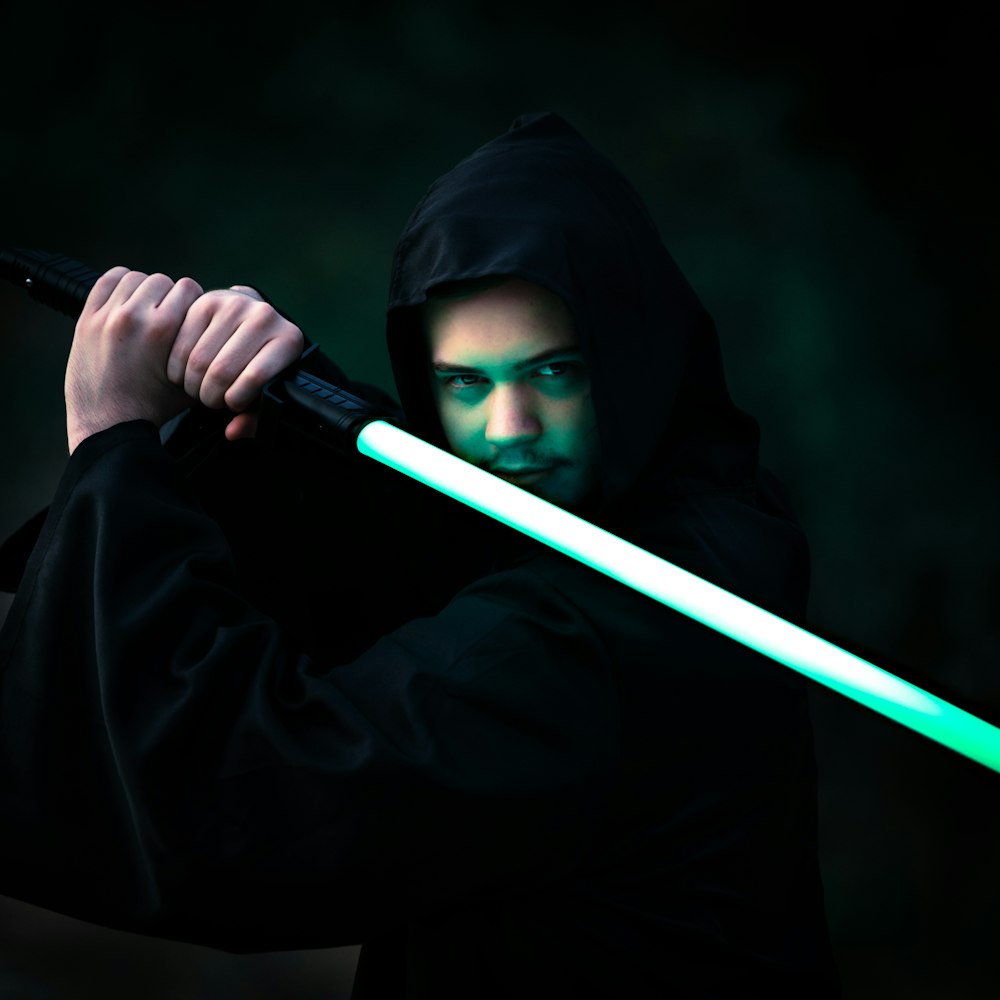 person in black hoodie holding blue stick