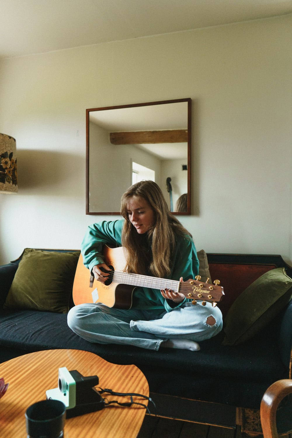 Femme en chemise à manches longues verte jouant de la guitare électrique blanche