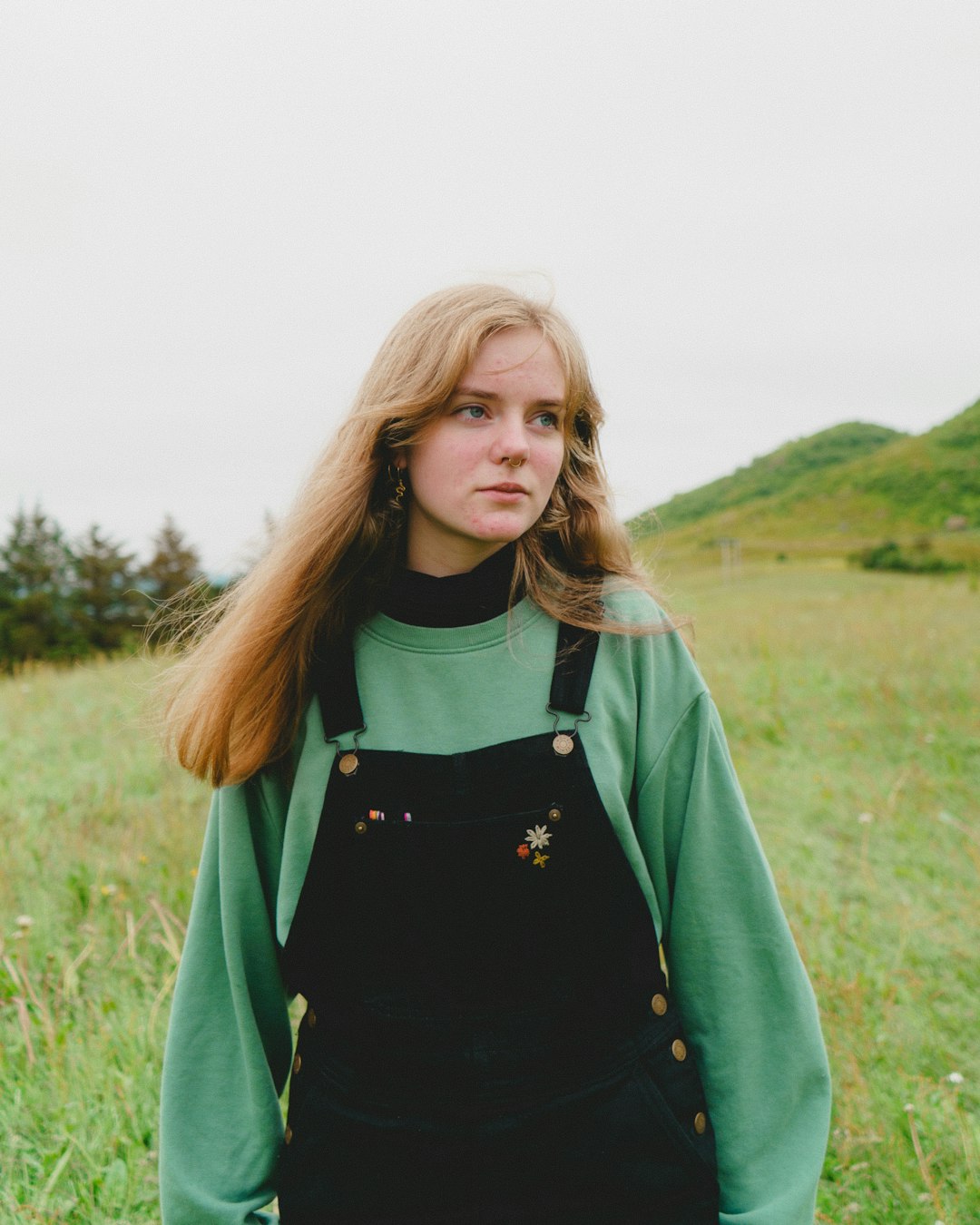 woman in green jacket standing on green grass field during daytime