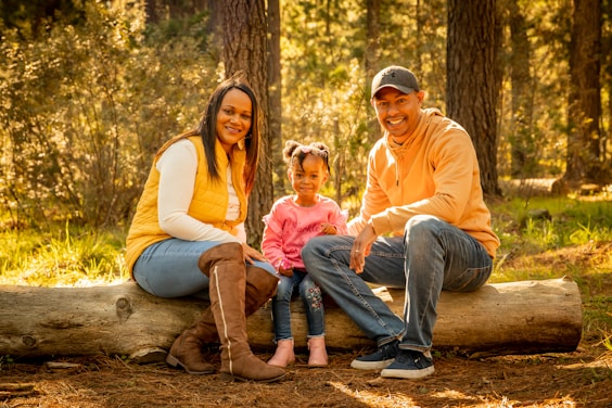 man and woman sitting on tree log during daytime
