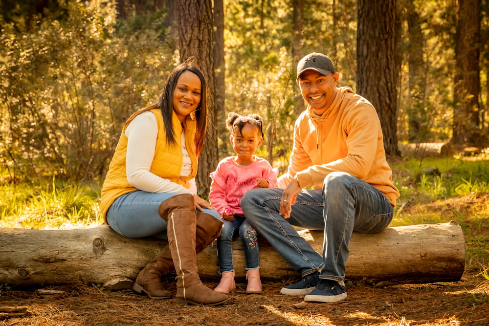 man and woman sitting on tree log during daytime