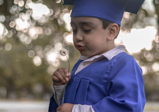 boy in blue academic dress and mortar board