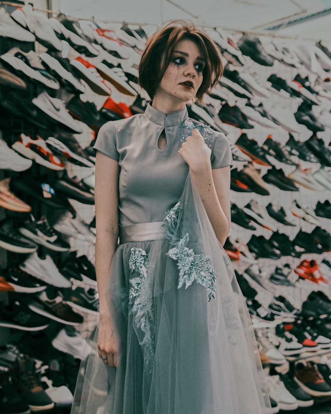 woman in gray and white dress standing near black and white wall