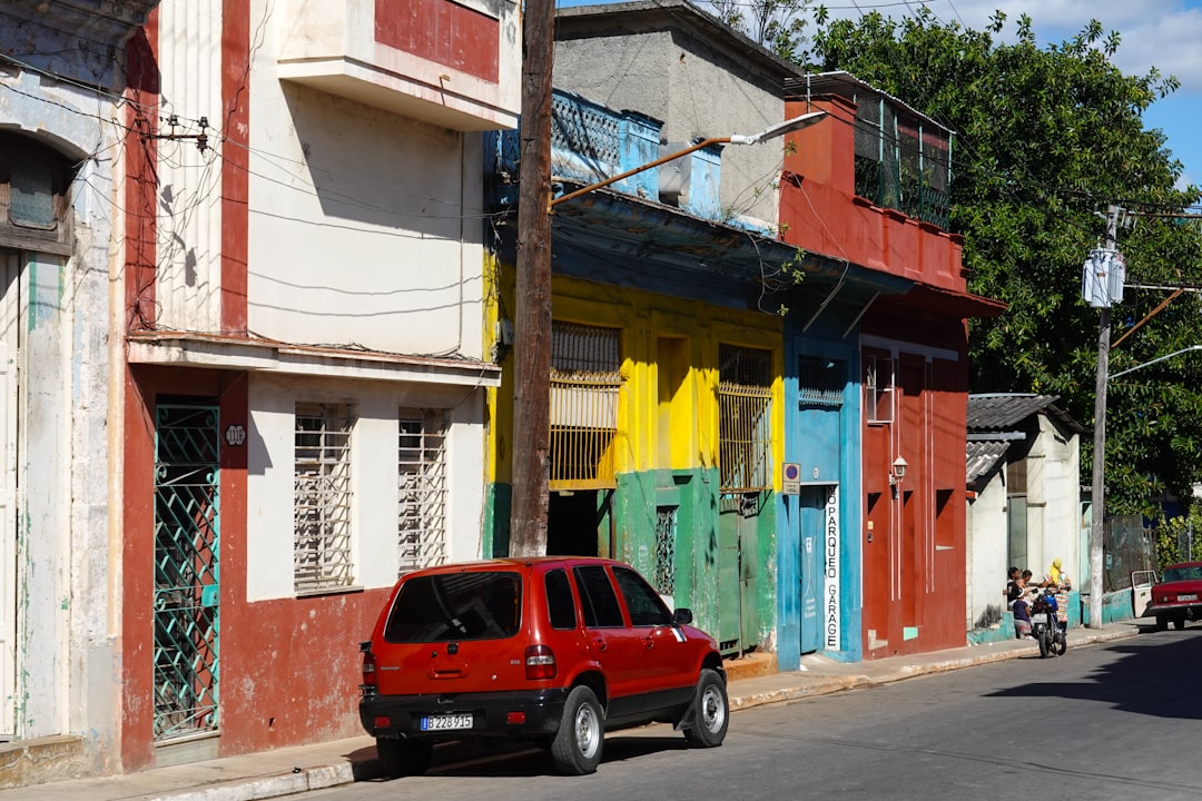 red suv parked beside blue and yellow concrete building during daytime