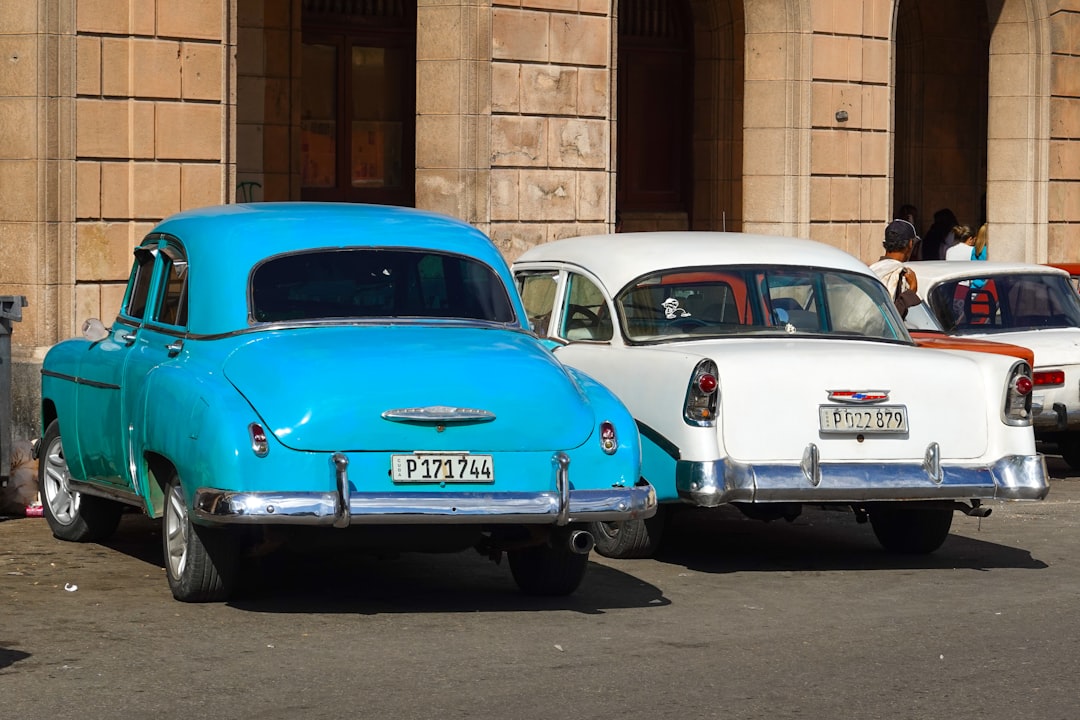 blue and white volkswagen beetle parked beside brown brick wall