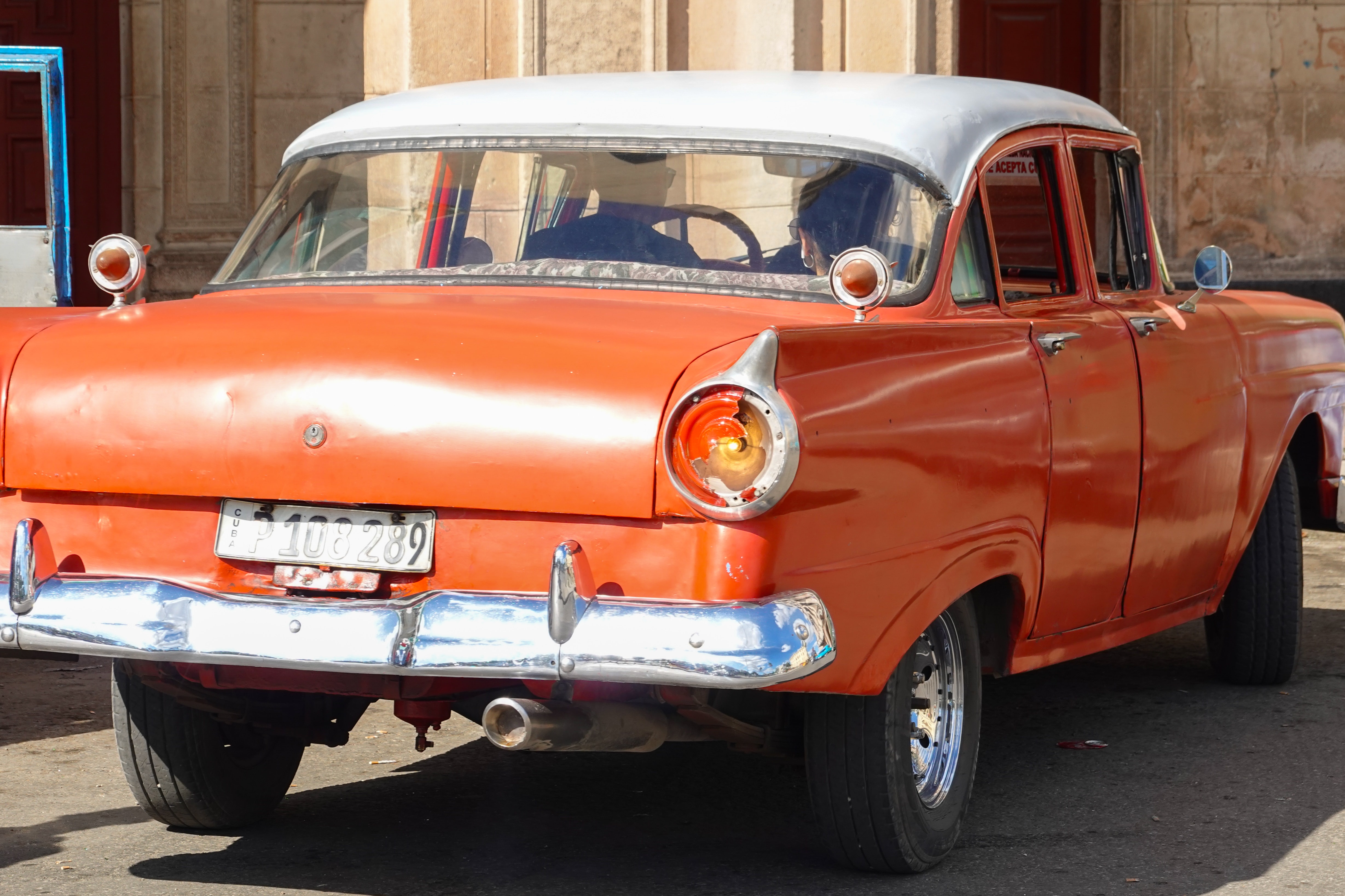 vintage red car parked on gray asphalt road during daytime