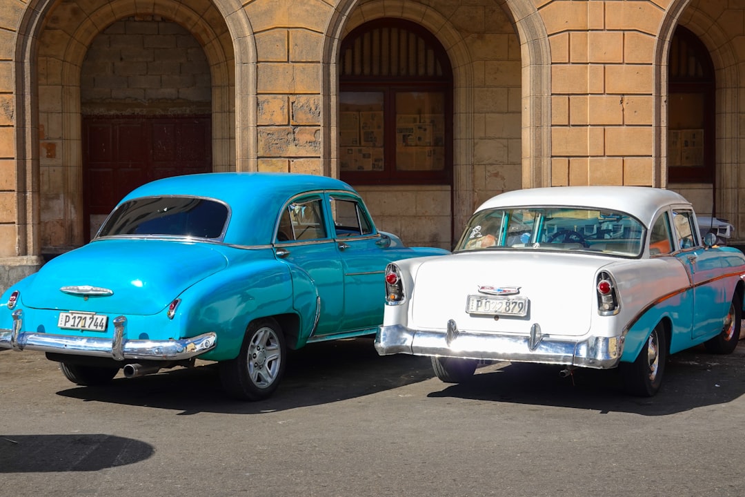 blue and white vintage car parked beside brown brick building