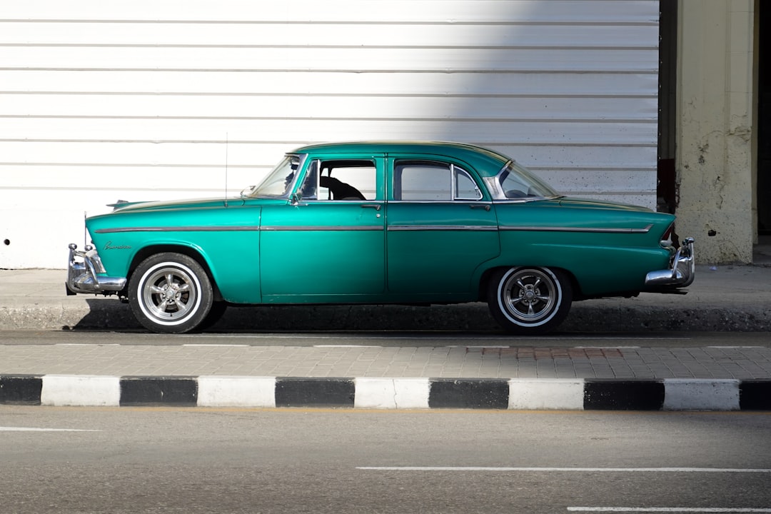 teal coupe parked on parking lot during daytime