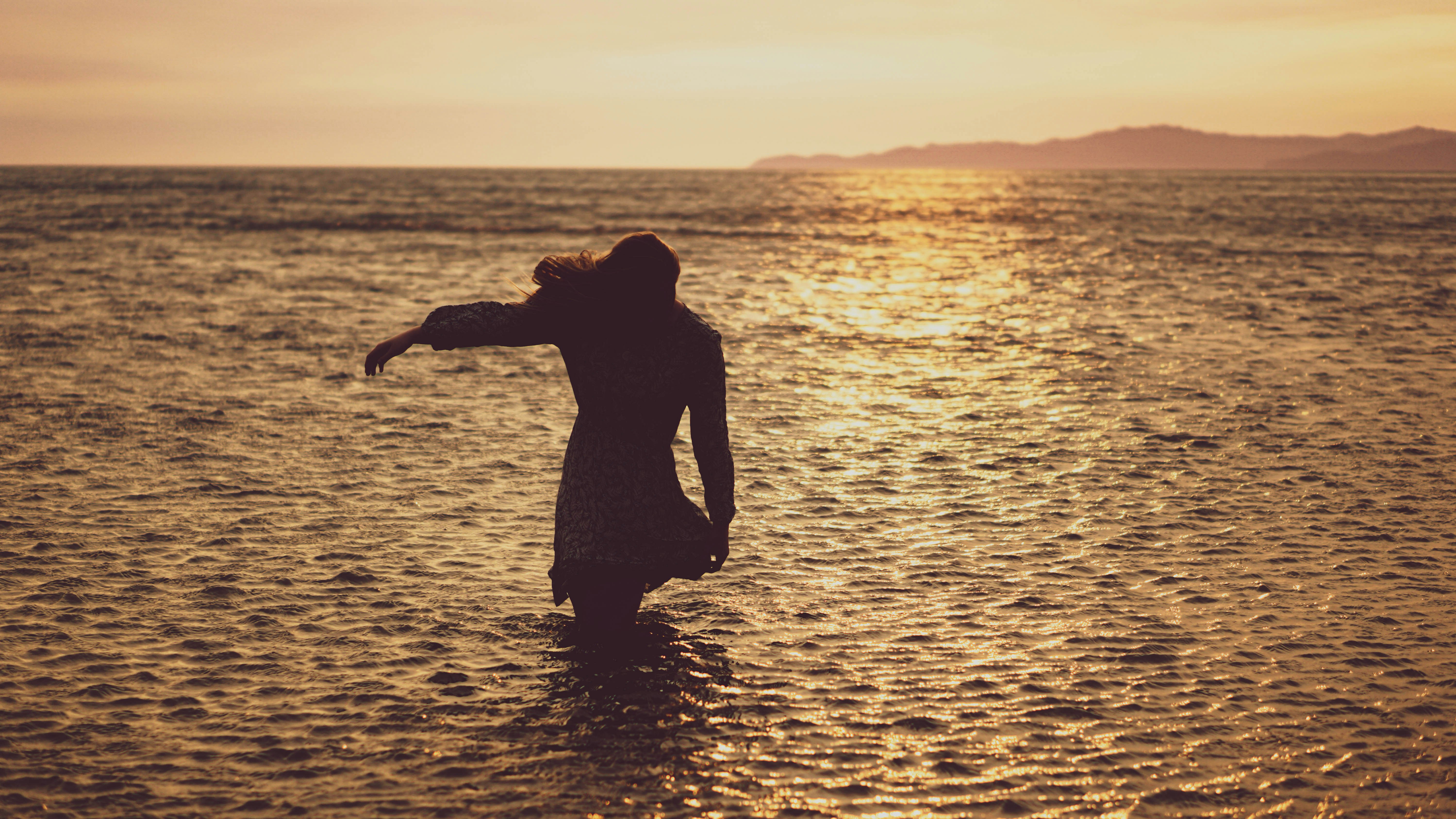 silhouette of man standing on water during sunset