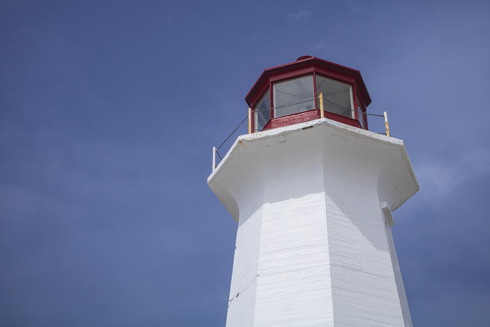 white and red concrete lighthouse under blue sky during daytime