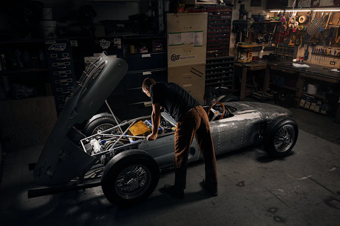 A skilled mechanic inspecting a car engine with tools in a well-lit garage.
