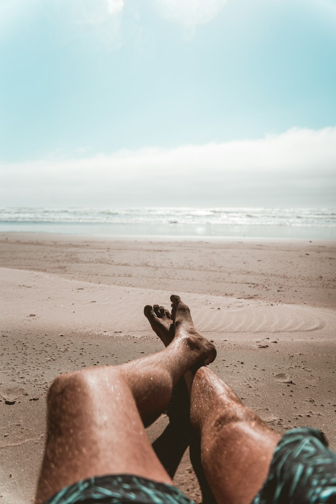 man sitting on brown sand near sea during daytime