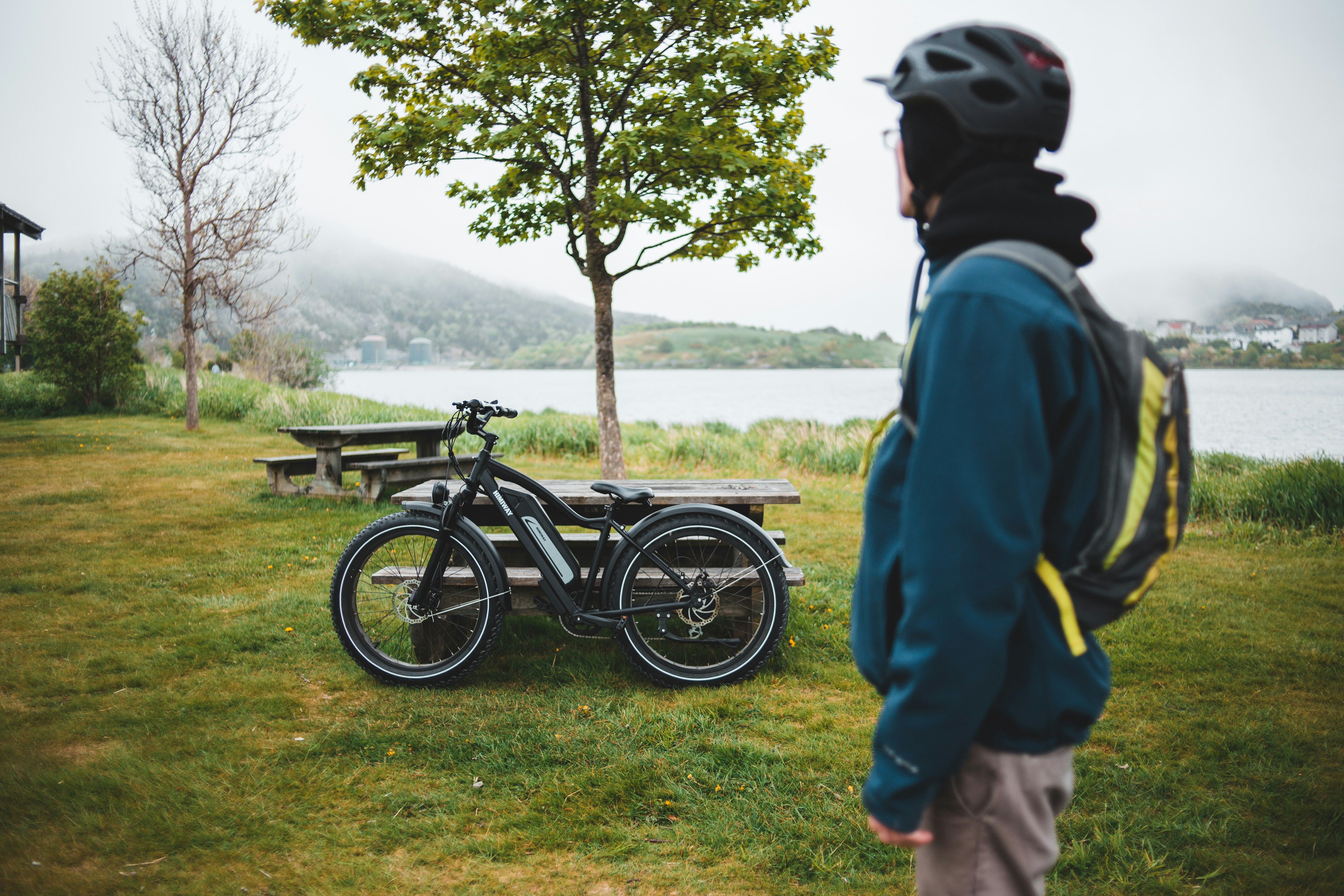 man in blue jacket and black pants standing beside black bicycle during daytime