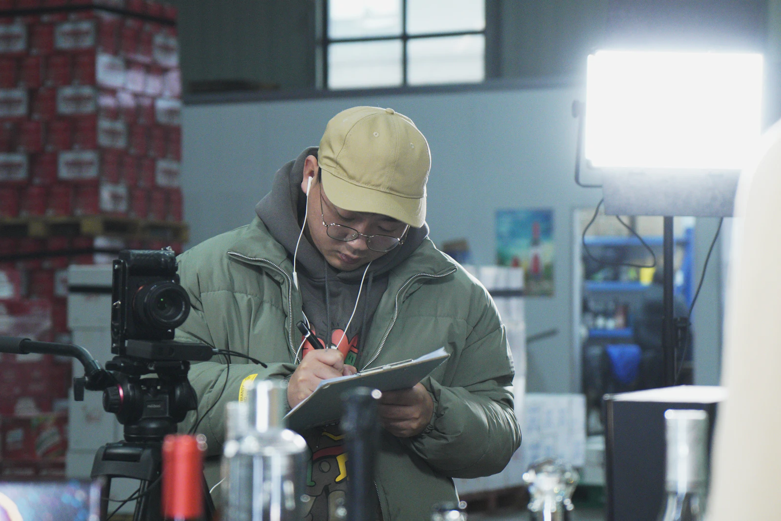 A person in an industrial setting writing on a paper form with a pen, representing real-time documentation and review at the point of work