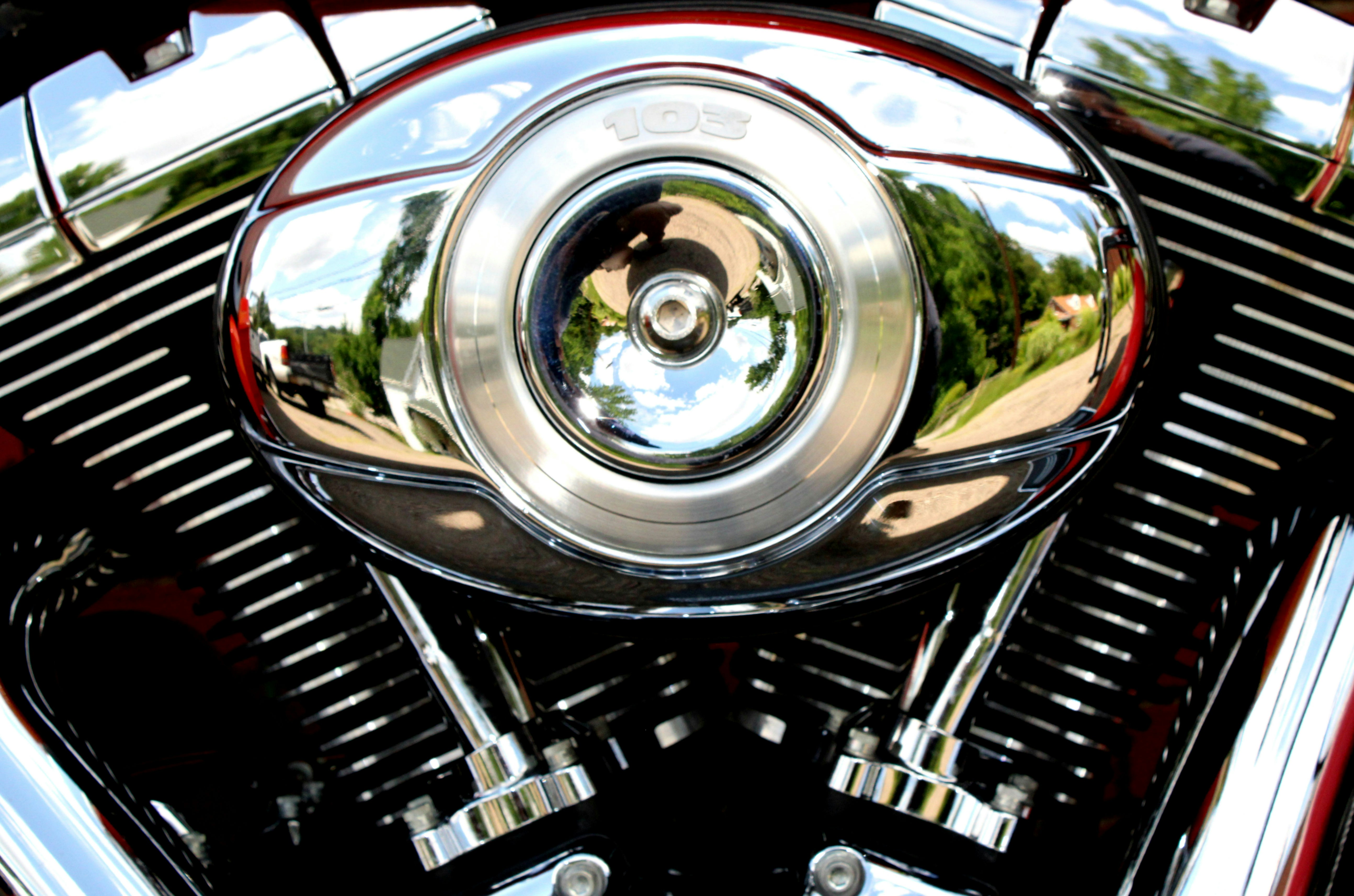 Close-up of a motorcycle's chrome engine gleaming under bright sunlight.