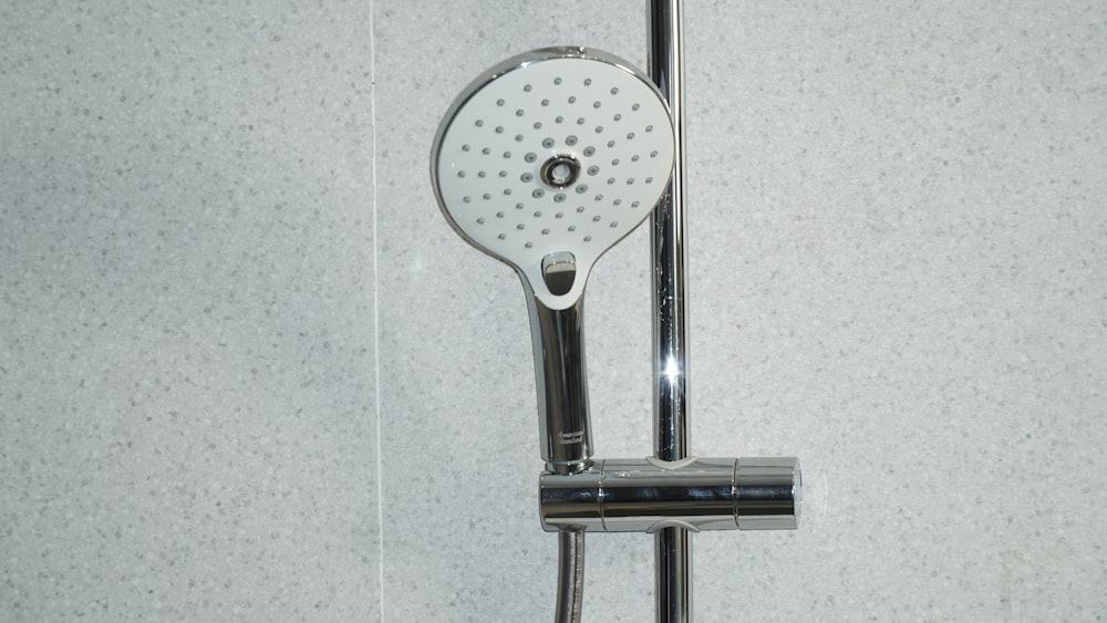 pommeau de douche en acier inoxydable sur carreaux de céramique blanche