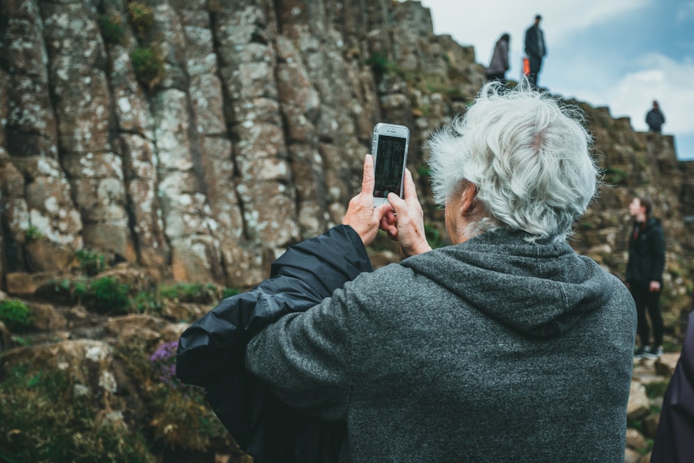 Mann in schwarzem Kapuzenpulli mit Smartphone