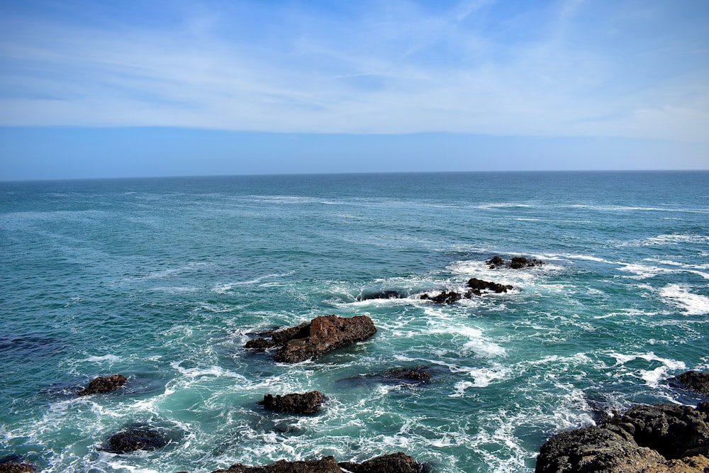 昼間の青空の下の海に浮かぶ茶色の岩層