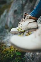 Close-up of worn hiking boots stepping on rocky terrain with a blurred mountain background