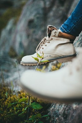 Close-up of trekking boots on a rocky path with wildflowers.