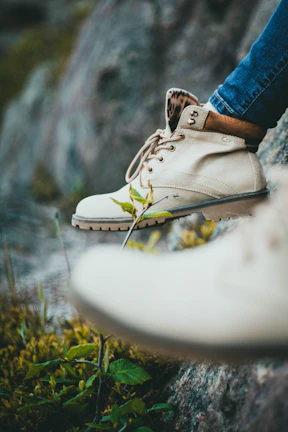 Close-up of rugged hiking boots on rocky terrain, dust swirling gently.
