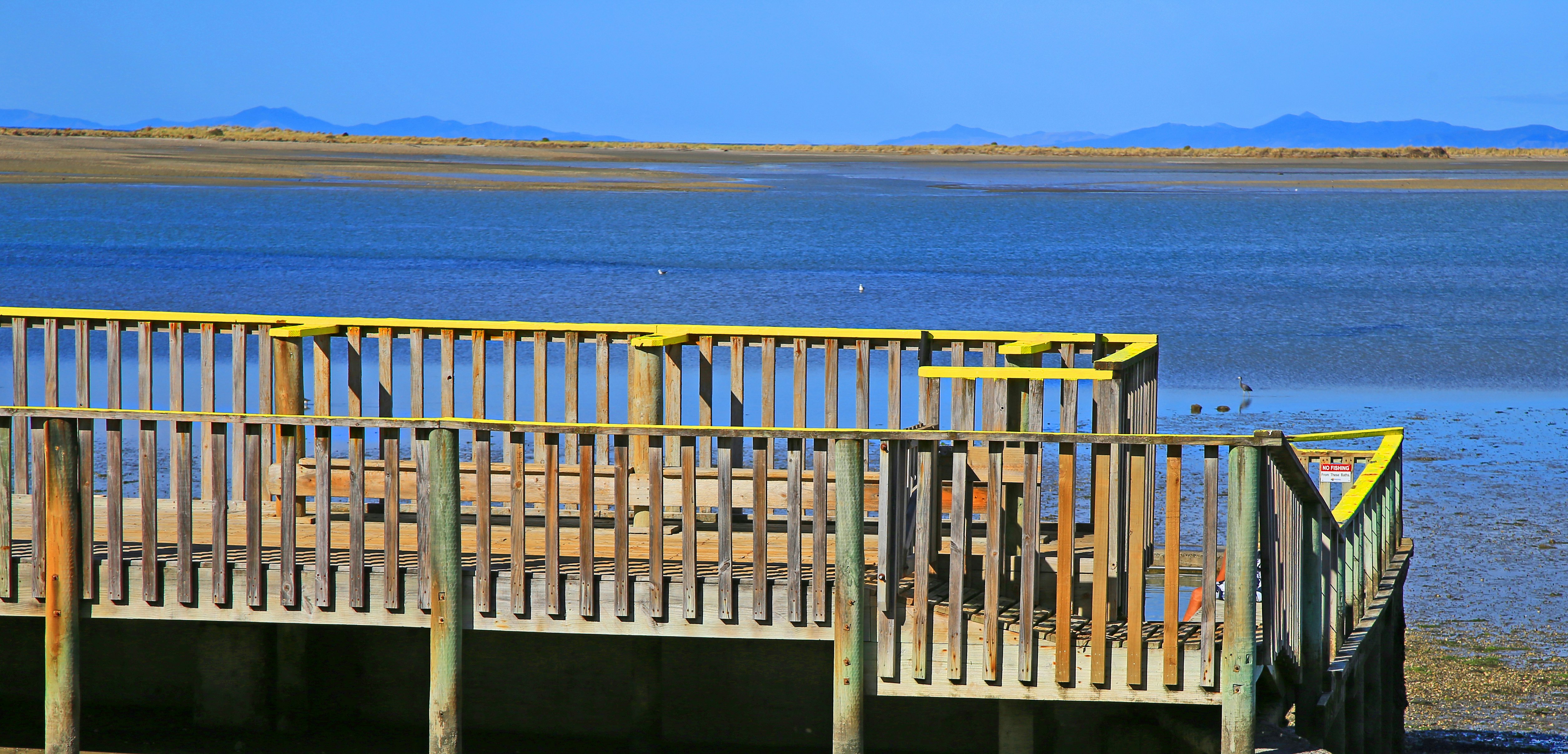 brown wooden fence near body of water during daytime