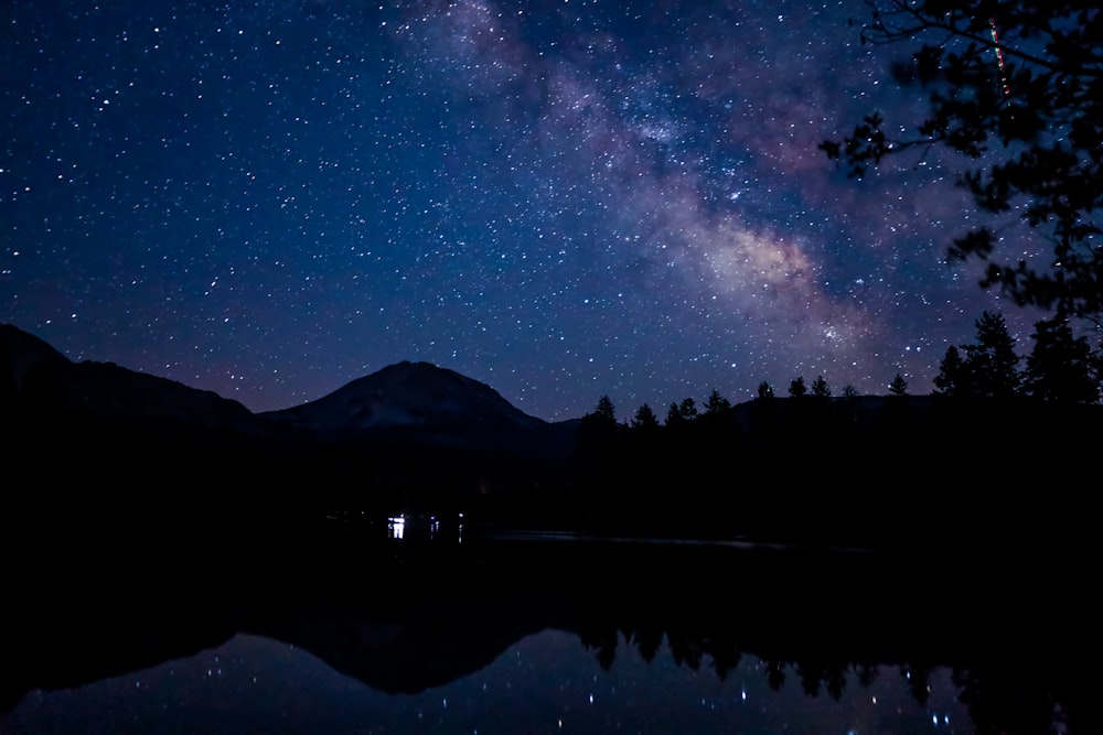 silhouette of mountain near body of water during night time