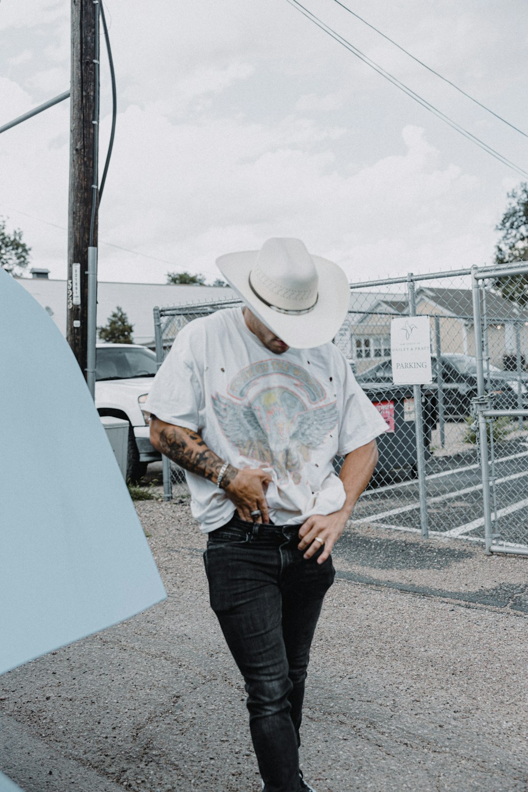 man in white cowboy hat and white and green floral button up t-shirt standing beside