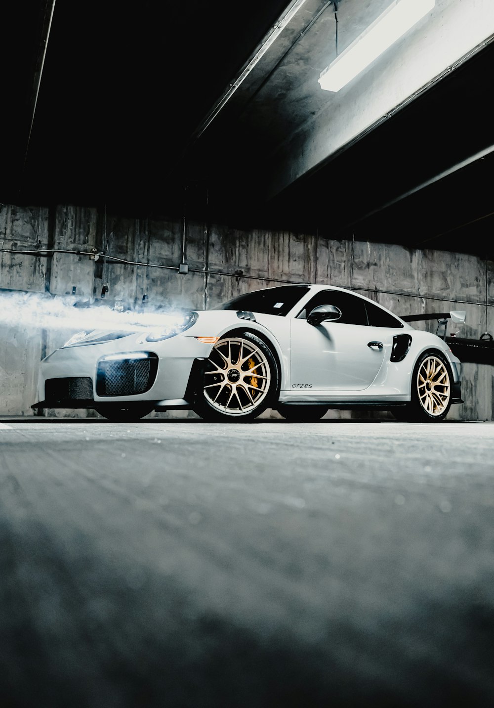 white and black porsche 911 parked on gray concrete floor