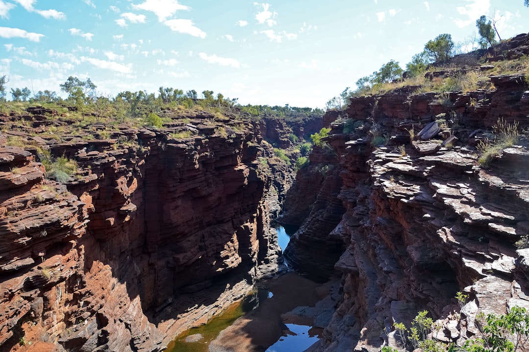 brown rocky mountain beside river under blue sky during daytime