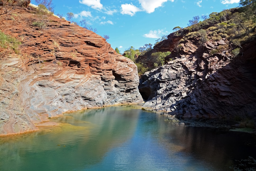 brown rocky mountain beside river under blue sky during daytime