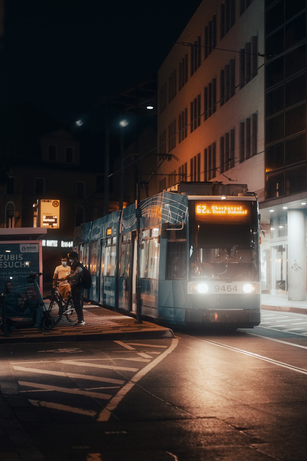 people walking on sidewalk near white and yellow tram during night time